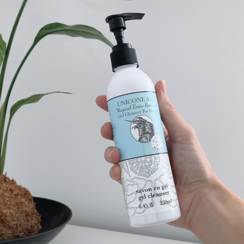 a woman holding a magical resin remover cleanser soap bottle